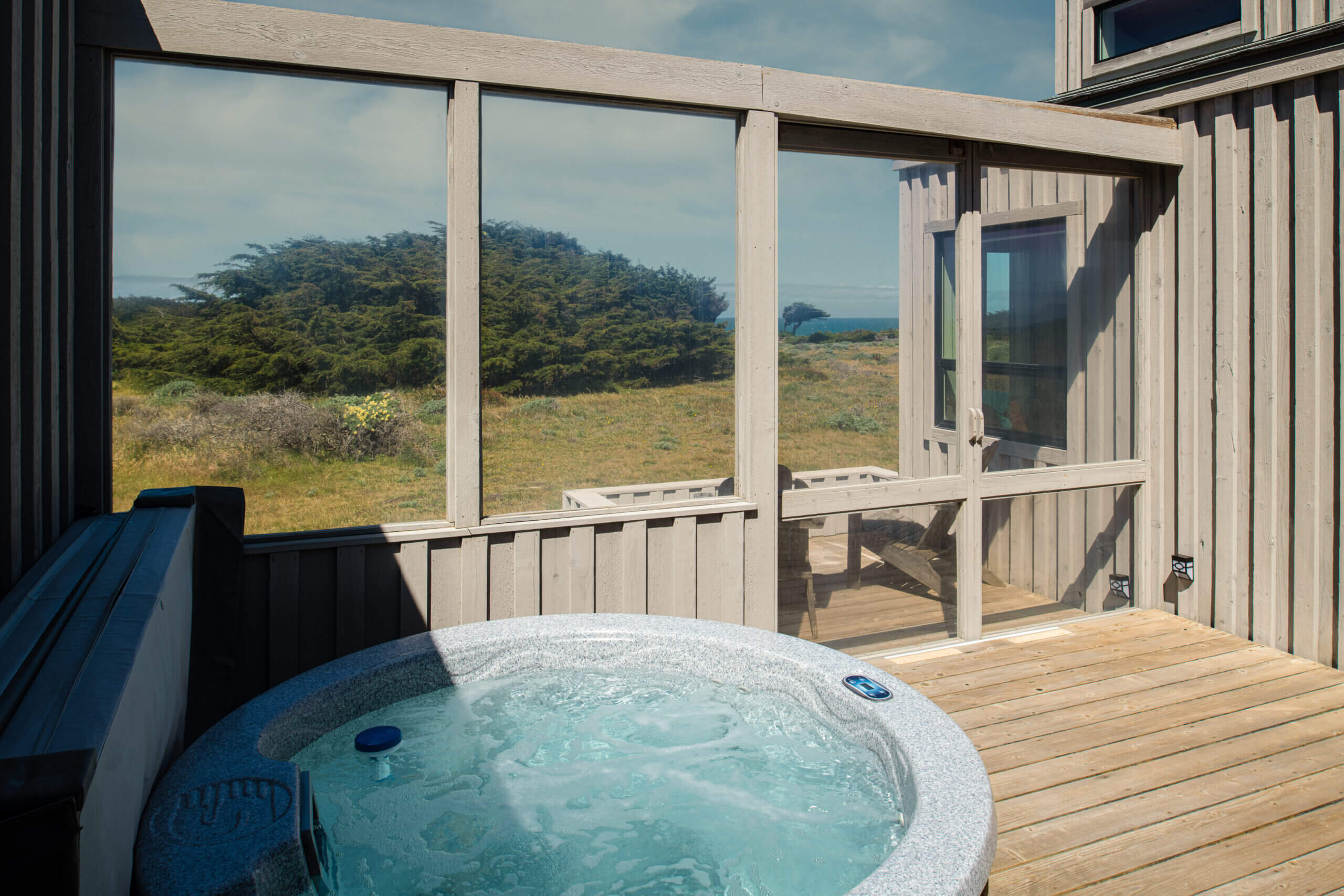 Bella Luna deck with hot tub and view of scrubby meadow and sea