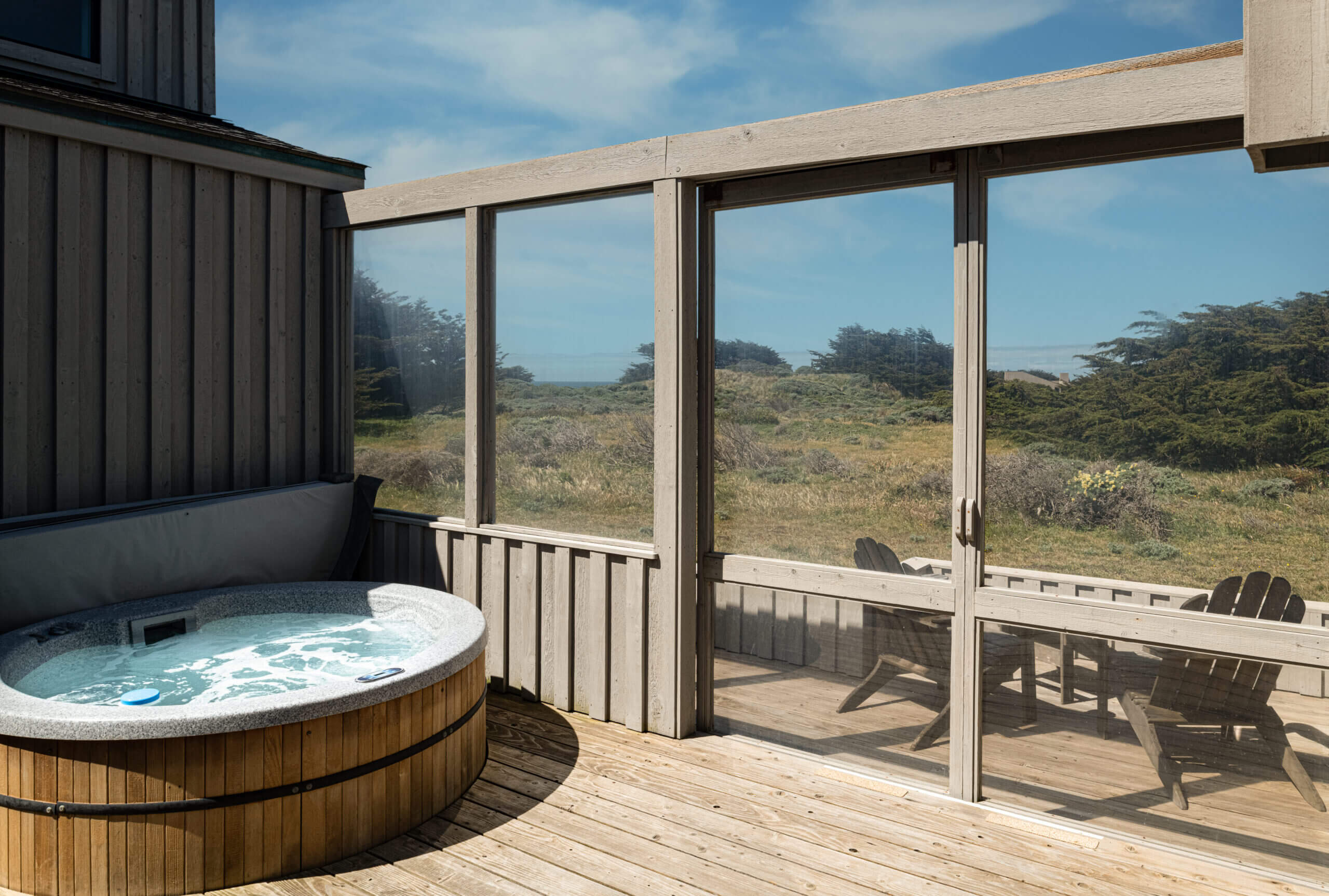 Bella Luna deck chairs with hot tub and view of scrubby meadow and sea