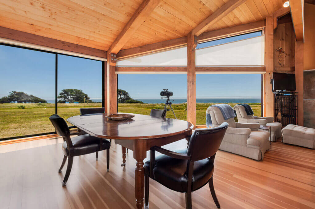 Tin Roof interior dining room large windows looking at ocean meadow