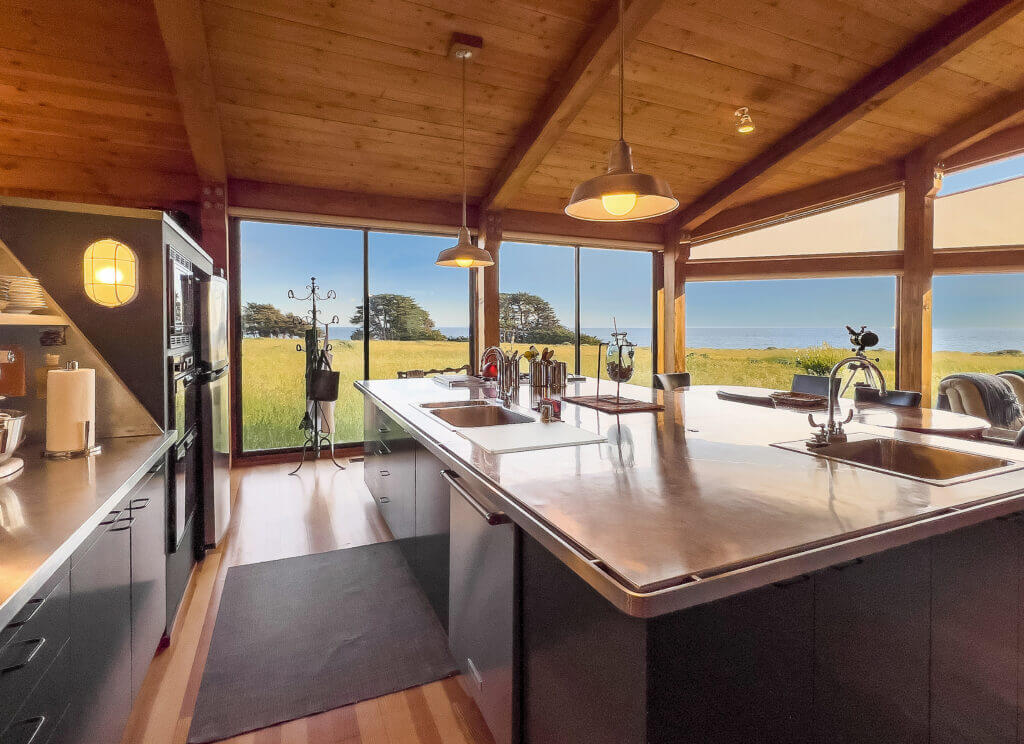 Tin Roof kitchen with large island and windows looking at ocean meadow