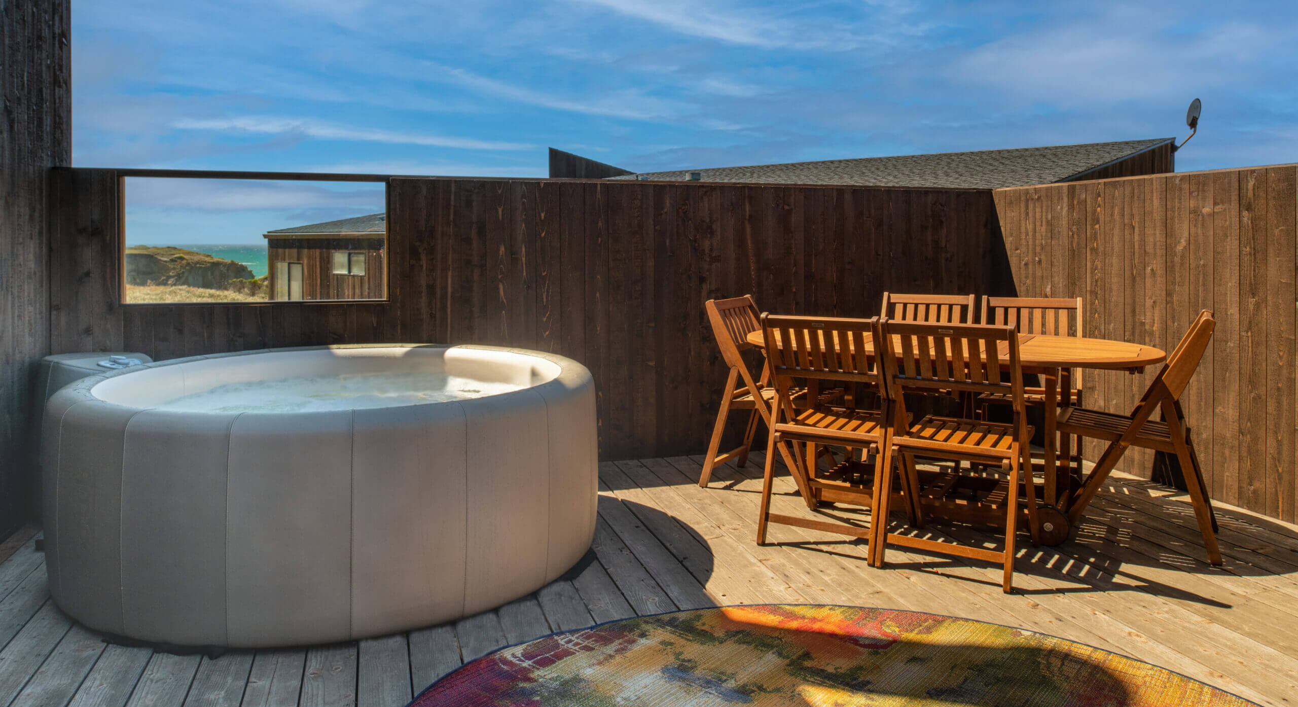 Piper's Dream exterior deck with hot tub and table against blue sky