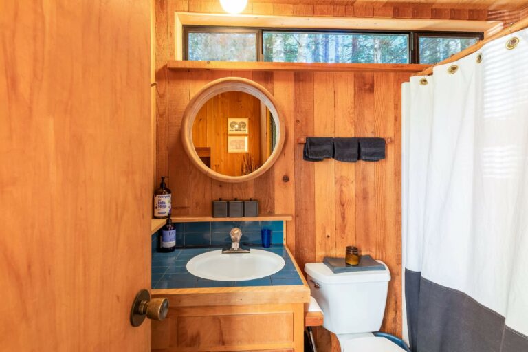 Paradiso - bright wood paneled bathroom with sink, toilet and shower curtain