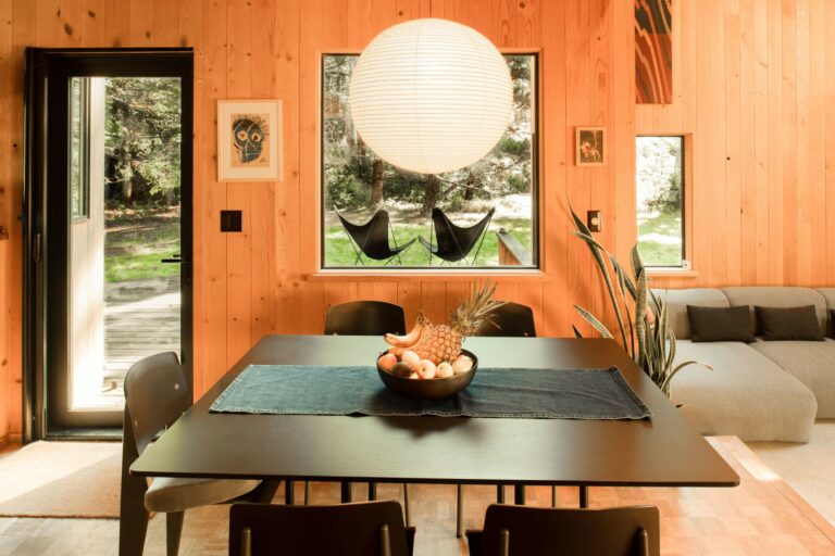 Paradiso - bright wood paneled dining area with black table and view of deck