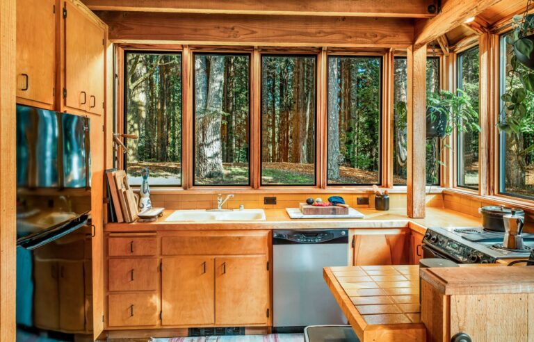 Paradiso - bright wood paneled kitchen with large windows looking at forest