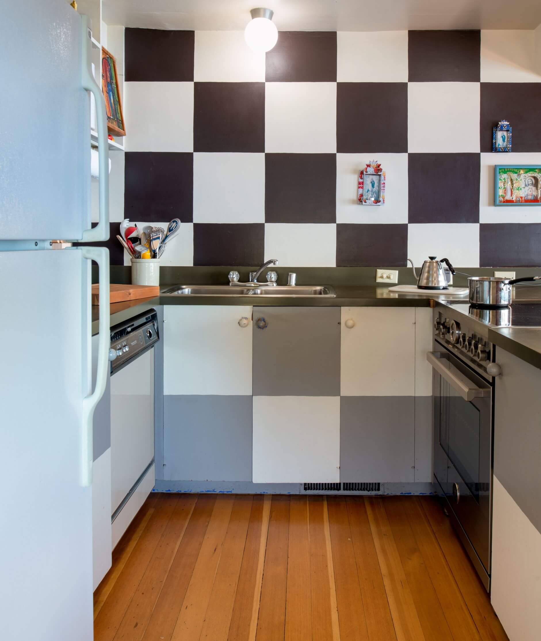 Moore Condo #9 - bright small kitchen with black, white and grey checkered patterned wall and cabinets and wood floor.